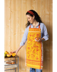 Orange fruit jacquard apron worn with blue jeans; visible red ties and patterned bib.