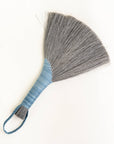 Gray tampico wing brush with blue striped wrap and braided leather loop