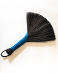Hand broom with dark bristles, bright blue handle, black leather cord loop