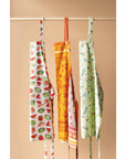 Three fruit-print aprons hanging: orange center, plus white side aprons with green accents.