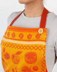 Orange fruit jacquard apron with red neck strap and wooden button at the bib.