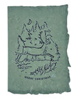 Christmas card with ink illustration of a winter cabin and “Merry Christmas” text
