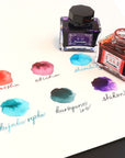 Japanese ink bottles with black caps and handwritten color swatches on paper