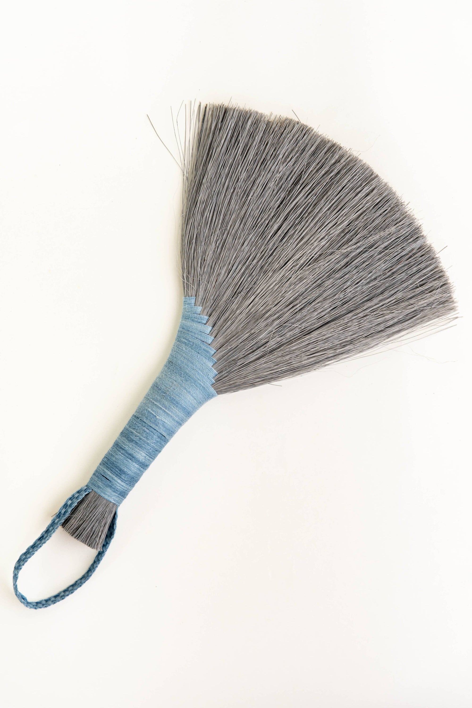 Handheld wing broom with gray fiber head, blue wrapped handle, and blue cord loop