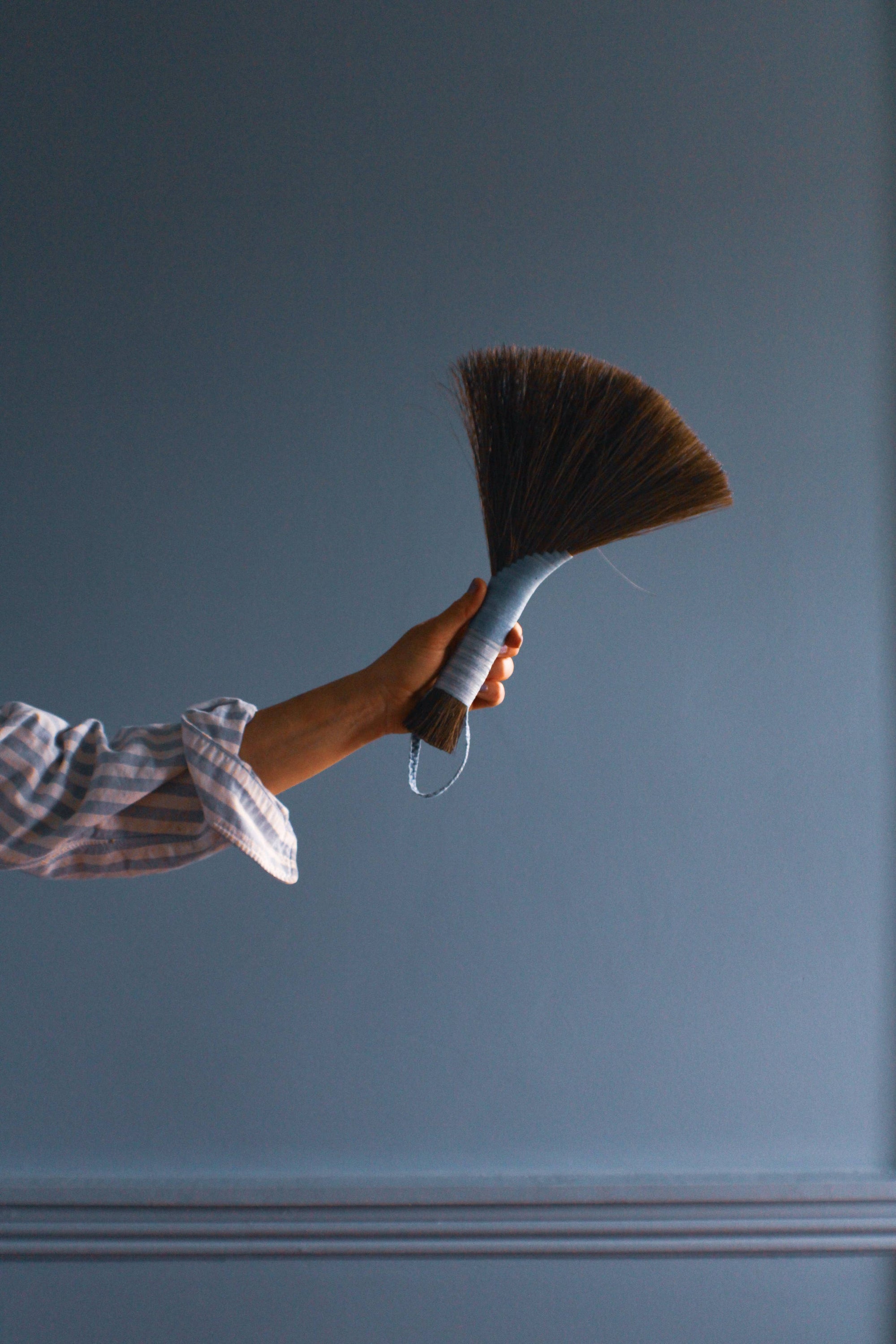 Tampico wing brush with dark bristles and striped handle held by hand