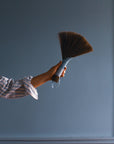 Tampico wing brush with dark bristles and striped handle held by hand