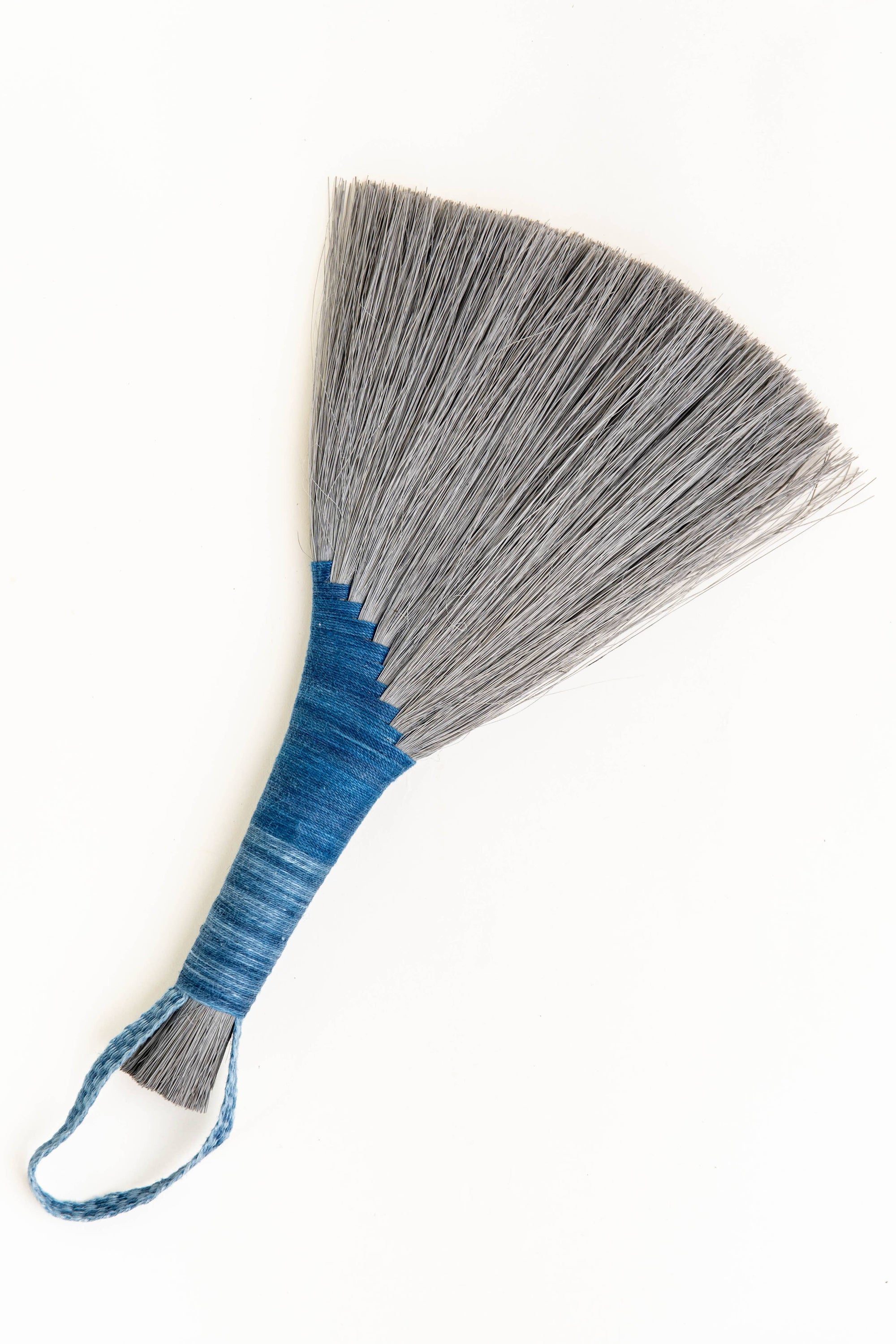 Handheld wing broom with gray fiber head, blue wrapped handle, and blue cord loop