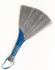 Gray tampico wing brush with blue striped wrap and braided leather loop