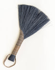 Handheld wing broom with dark gray fiber head, brown wrapped handle, and dark cord loop