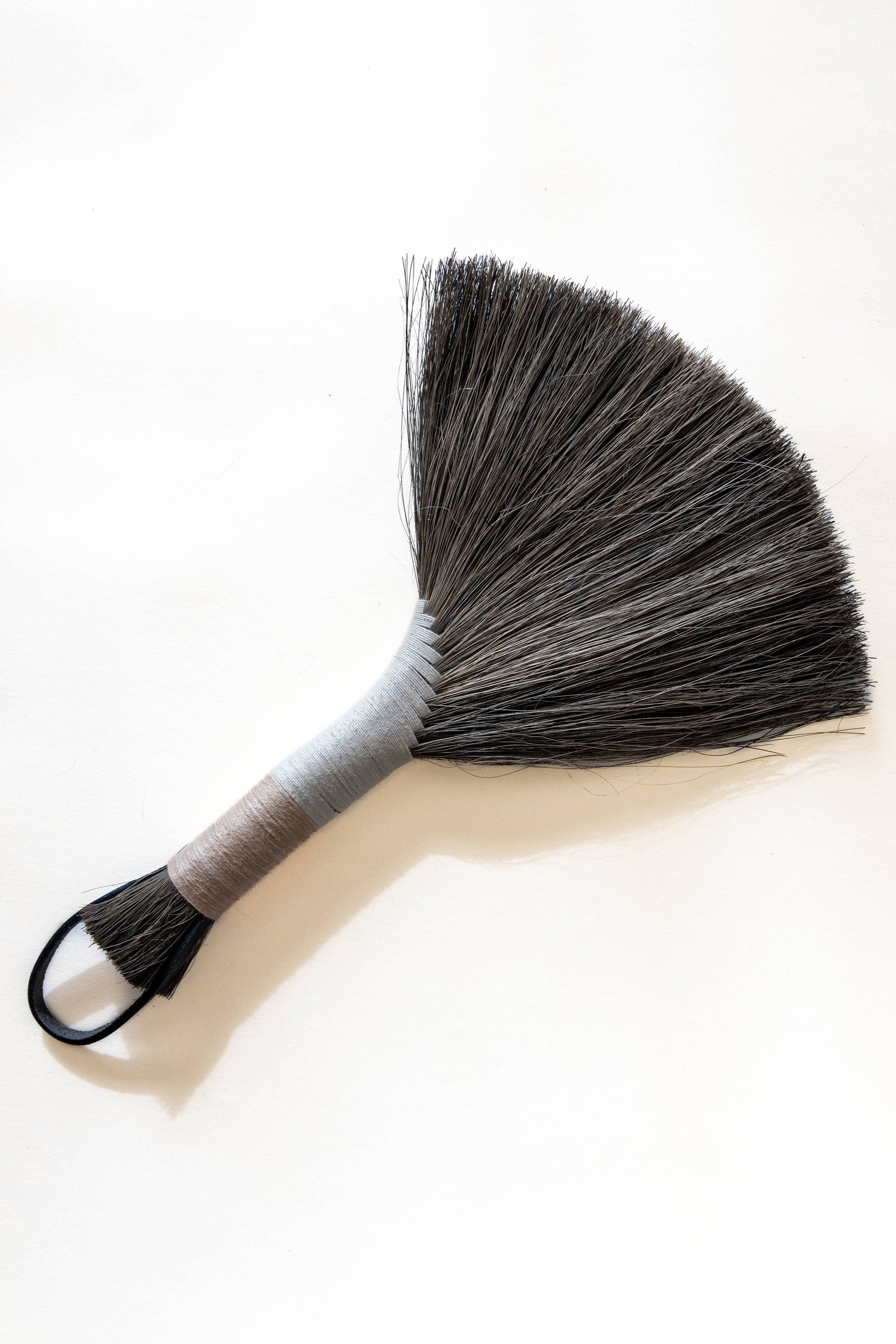 Tampico wing brush with dark bristles, silver-gray handle, and black leather cord loop