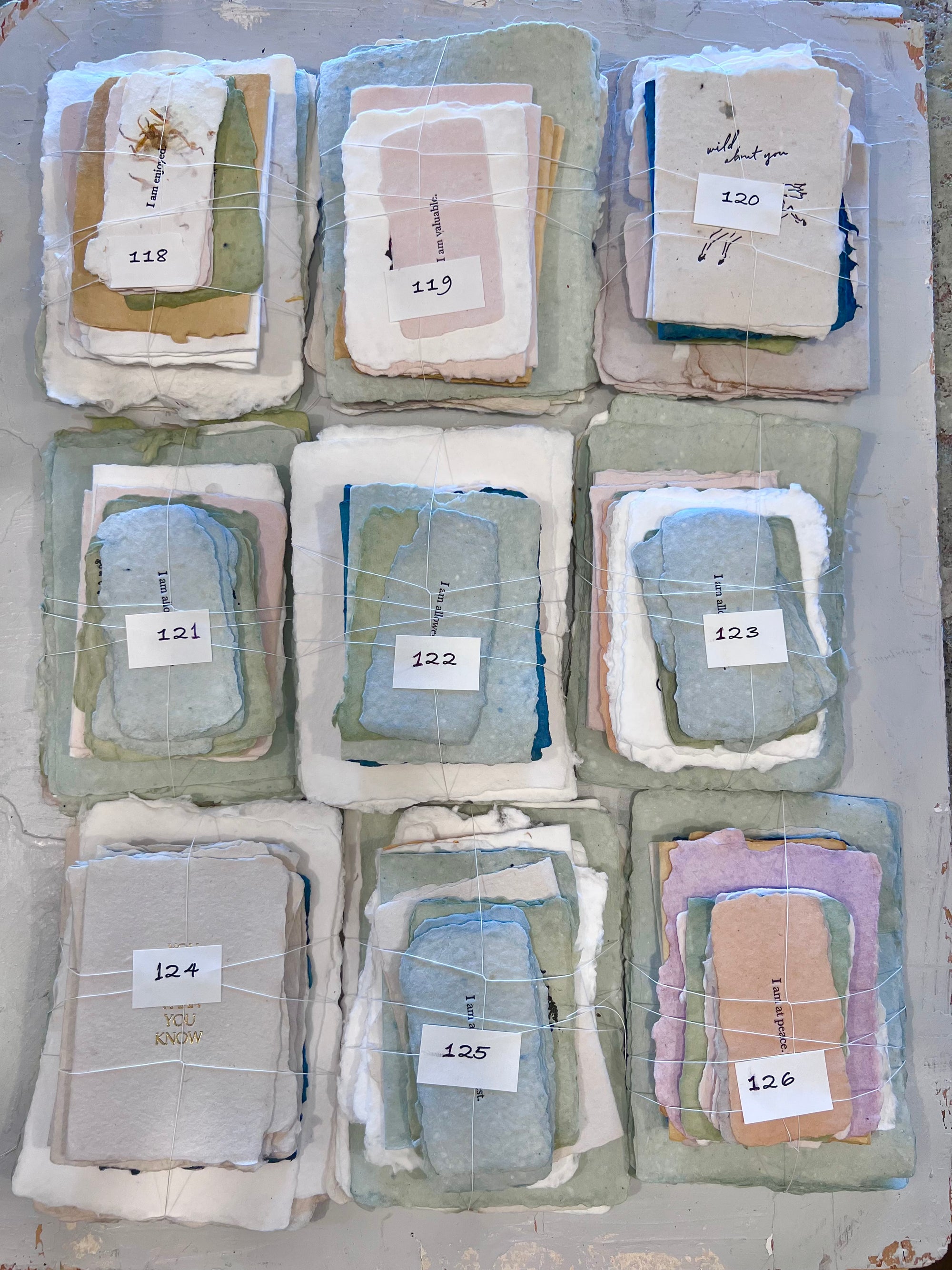 Assorted fabric bundles with numbers 118–126, wrapped in paper sleeves, mixed colors