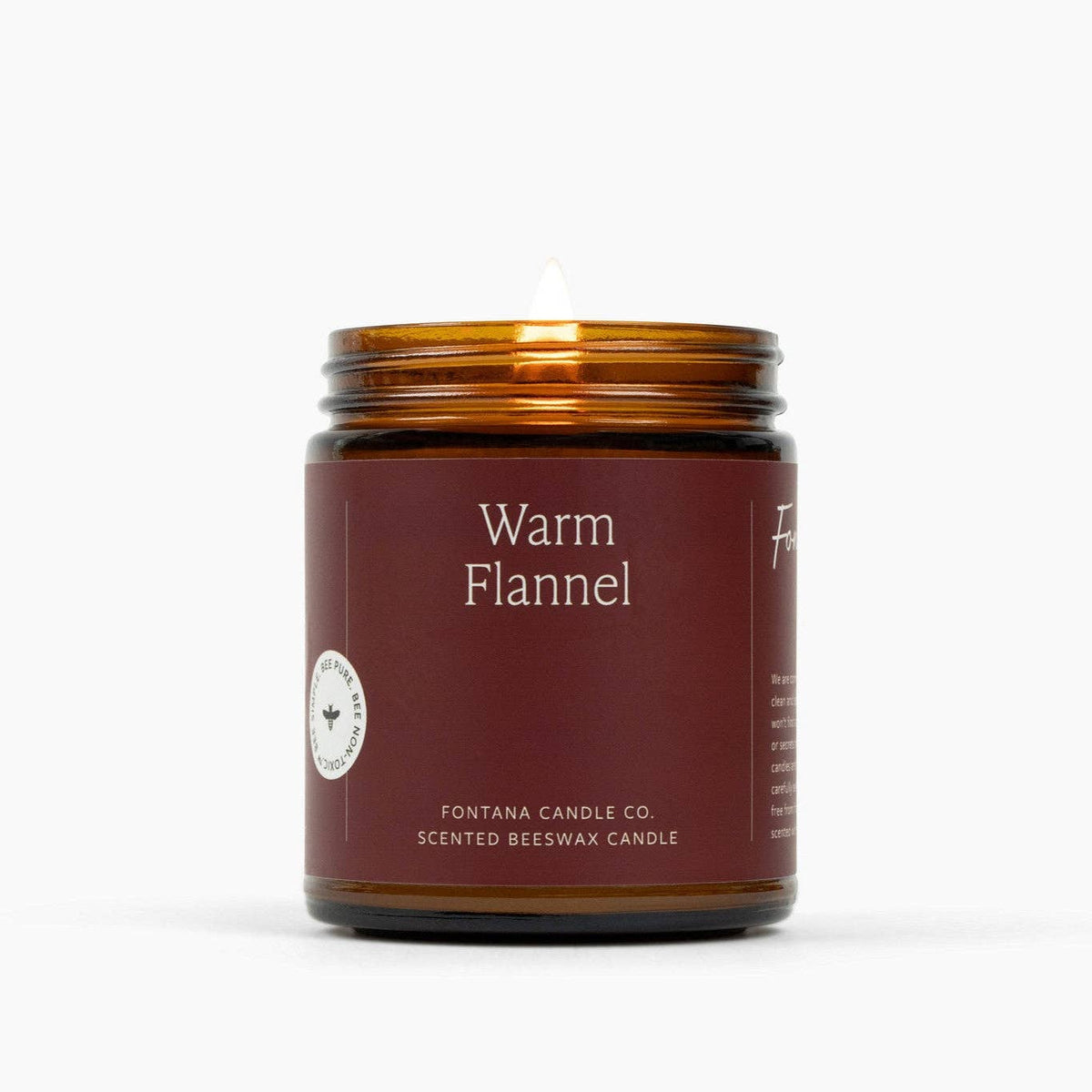 Warm Flannel scented beeswax candle in brown glass jar with flame