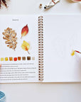 Autumn watercolor workbook open to leaf study page with watercolor samples and color swatches