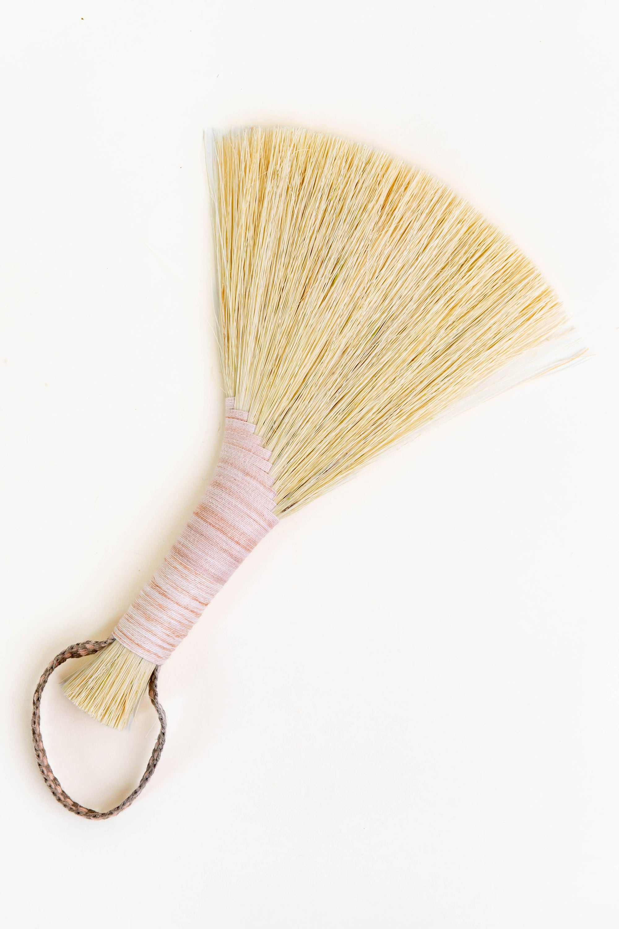 Wing broom with pink wrapped handle and brown leather cord loop