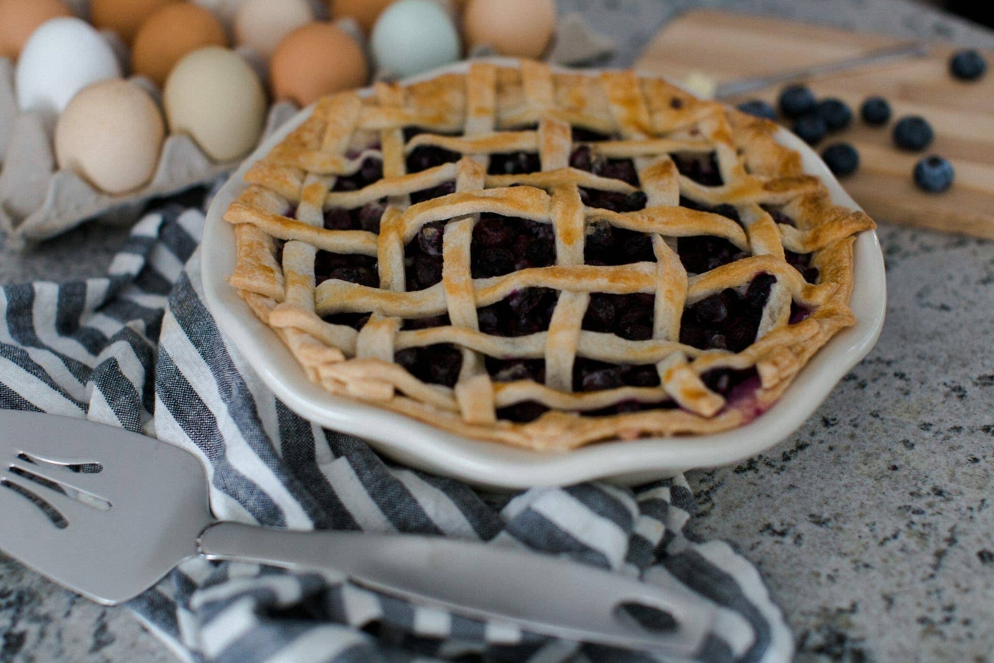 Frilly pie plate holding lattice berry pie in a white shallow dish