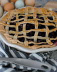 Frilly pie plate holding lattice berry pie in a white shallow dish