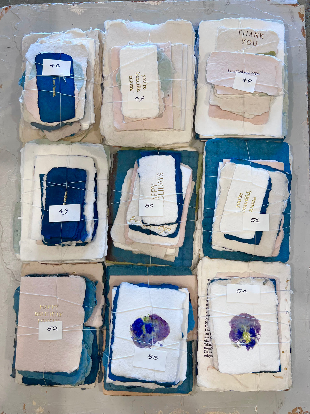 Assorted folded fabric bundles labeled 046–054, including blue, white, and floral designs