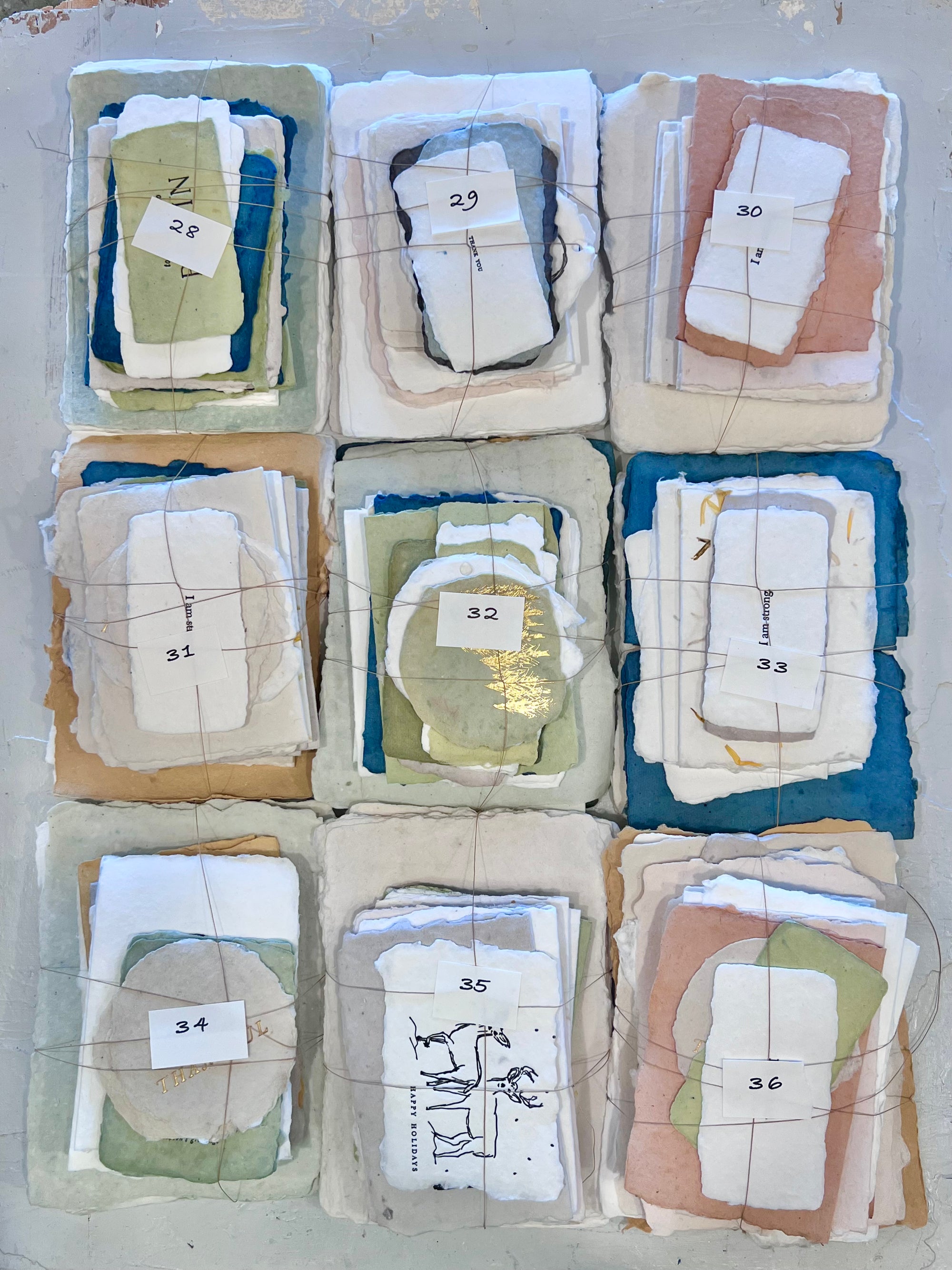 Assorted fabric bundle squares in blue, white, tan, and green, numbered 28–36