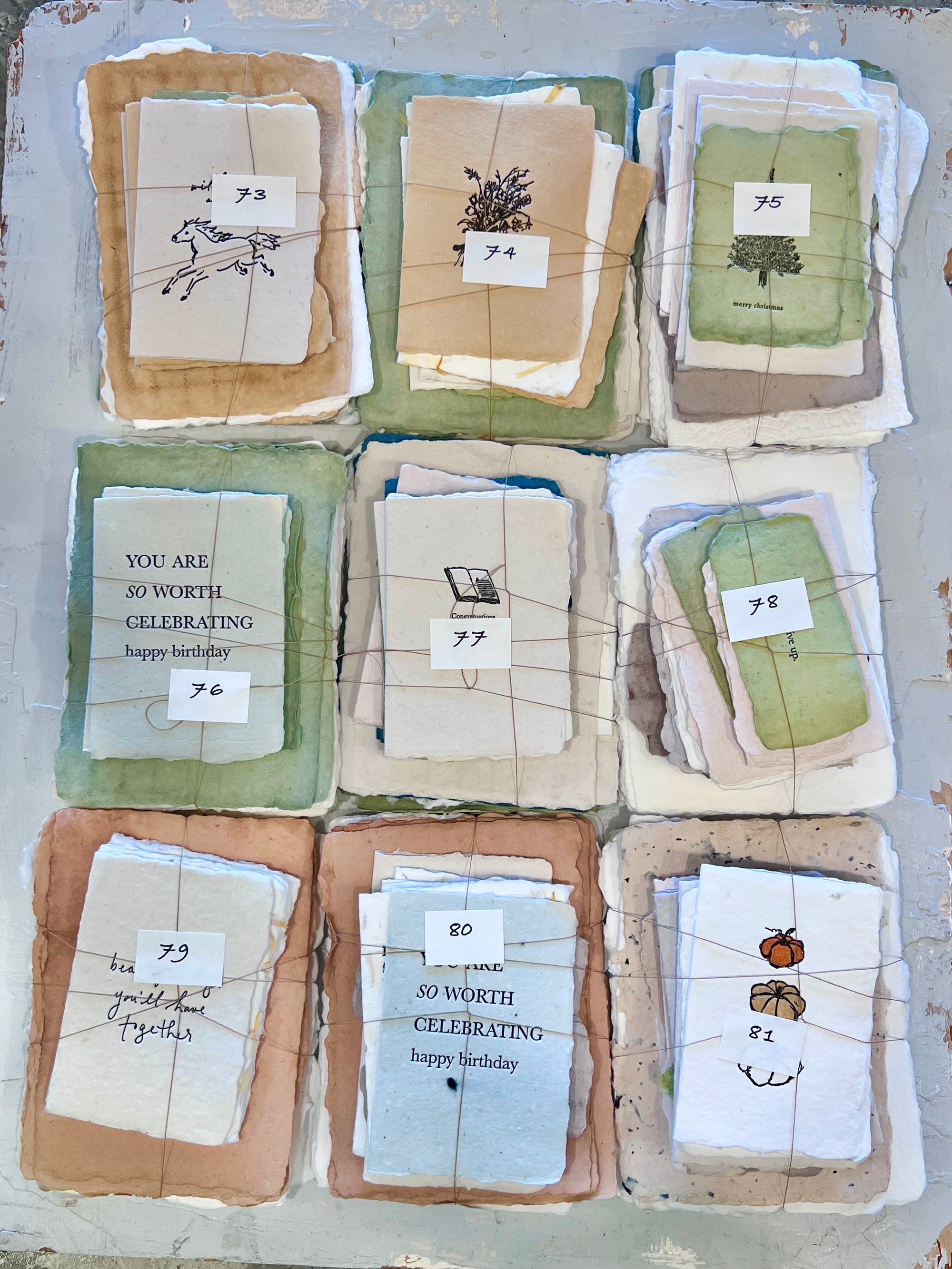 Assorted greeting card bundles with various illustrated cards, each bundle tied with twine