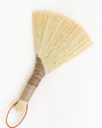 Handheld wing broom with light straw fiber head and brown leather cord loop
