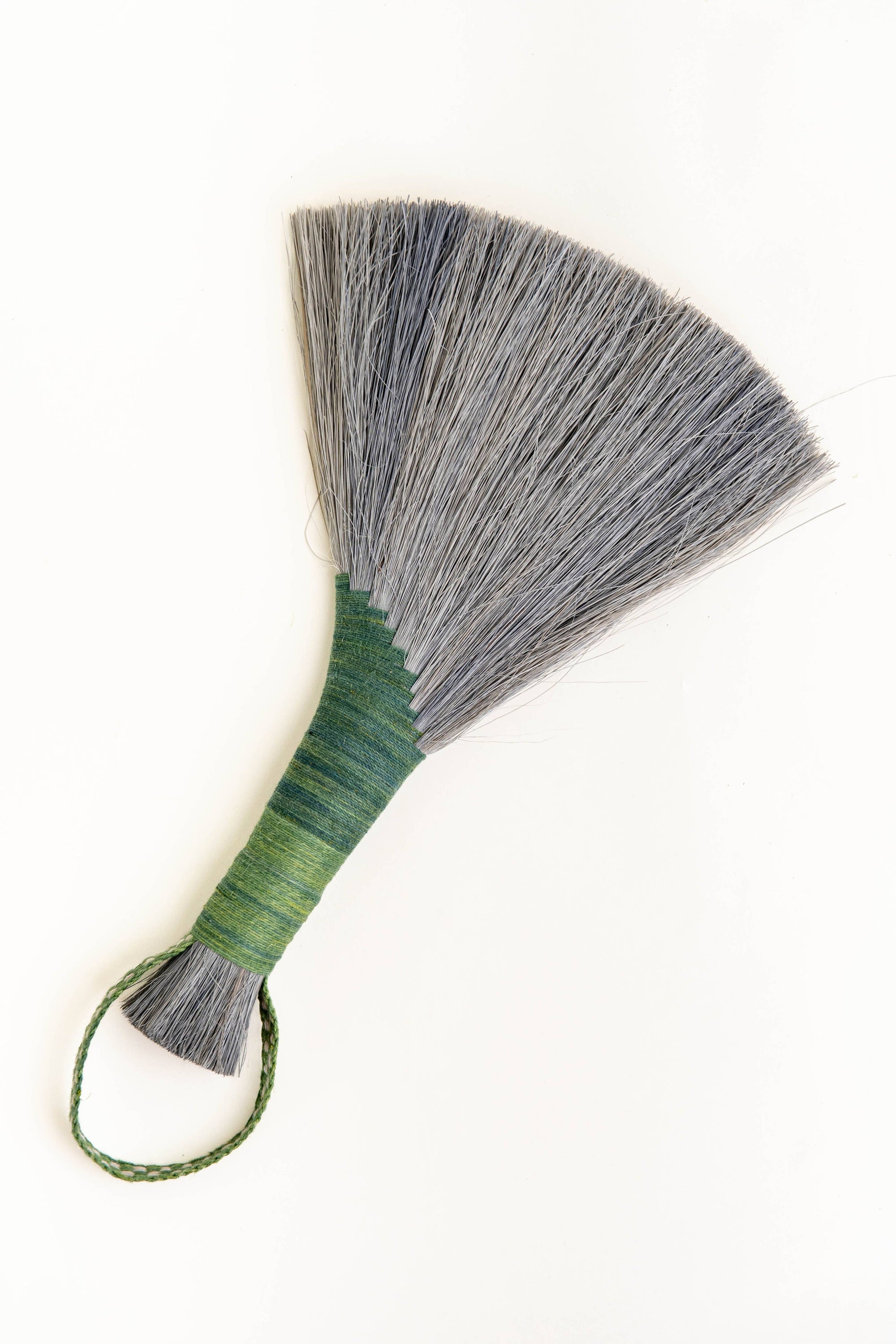 Handheld wing broom with gray fiber head, green wrapped handle, and green cord loop