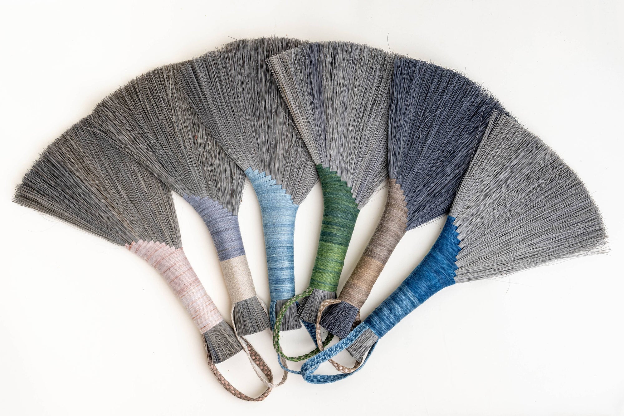 Fan array of wing brooms with gray, blue, green, pink, and navy fiber heads