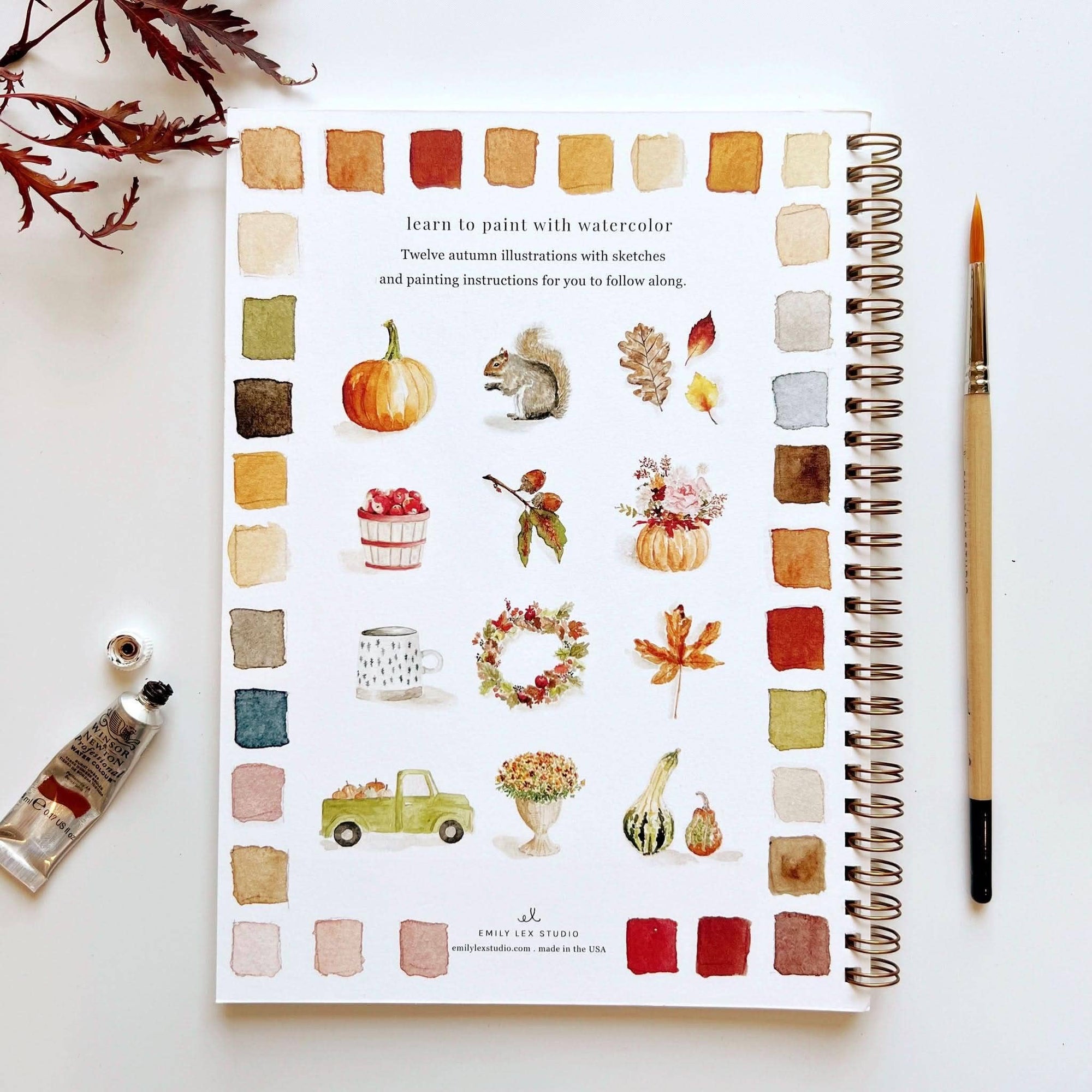 Autumn watercolor workbook open to instruction page with watercolor illustrations and swatches